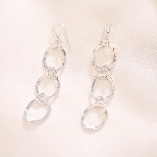 עגילי כסף תלויים בעבודת יד מסטודיו שירו, המציגים את התנועה הקלילה של החישוקים המשולבים בגימור איכותי.