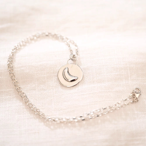 תליון ירח מכסף סטרלינג על שרשרת עדינה, עיצוב ייחודי המשלב פלטה עגולה למראה של ירח מלא המאיר בלילה.