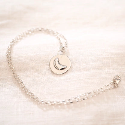 תליון ירח מכסף סטרלינג על שרשרת עדינה, עיצוב ייחודי המשלב פלטה עגולה למראה של ירח מלא המאיר בלילה.