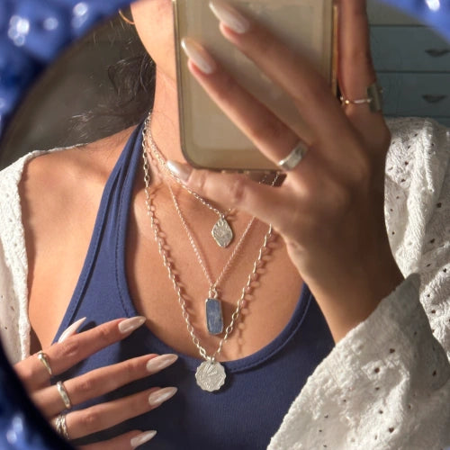 שרשרת קיאנייט כחולה בשילוב שרשראות כסף נוספות במראה שכבות על דוגמנית, תכשיט בעל גוון כחול עמוק וייחודי.