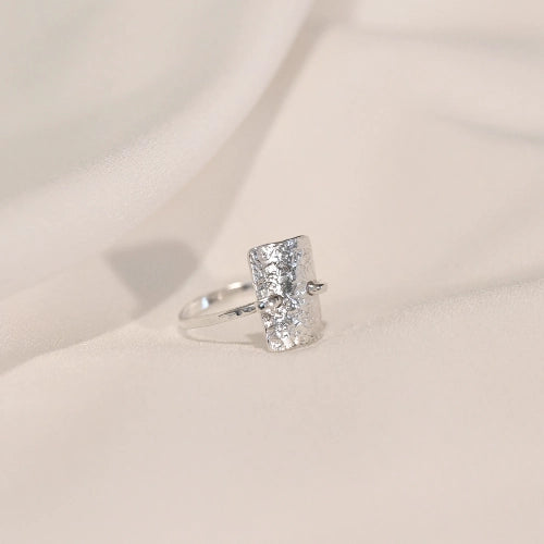 טבעת כסף סטרלינג מרוקעת במבט מהצד, מדגישה את הטקסטורה הייחודית והניגוד בין הקווים הישרים לקימורים העדינים.