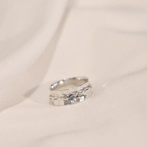 טבעת כסף סטרלינג עם אלמנט מסתובב בעיצוב צמה אומנותי, פריט אלגנטי בעל מגע מדיטטיבי המעניק תחושת שלווה ומיקוד.