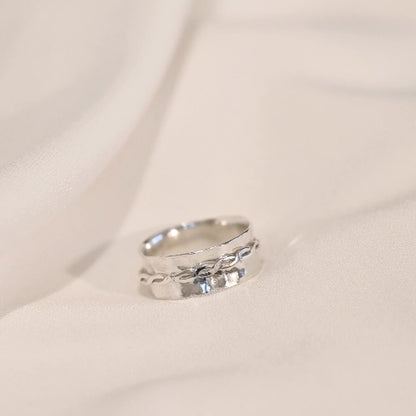 טבעת כסף סטרלינג עם אלמנט מסתובב בעיצוב צמה אומנותי, פריט אלגנטי בעל מגע מדיטטיבי המעניק תחושת שלווה ומיקוד.