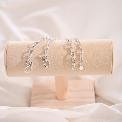 צמיד לולאות מרובעות מוצג על מעמד תכשיטים מקטיפה, מדגיש את הברק של הכסף והגימור המוקפד.