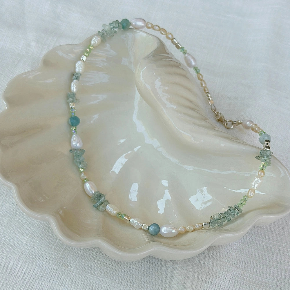 שרשרת פנינים ואבני אקוווה מרין בתוך קונכייה קרמית, מראה אורגני וקלאסי מקולקציית הקיץ של שירו.