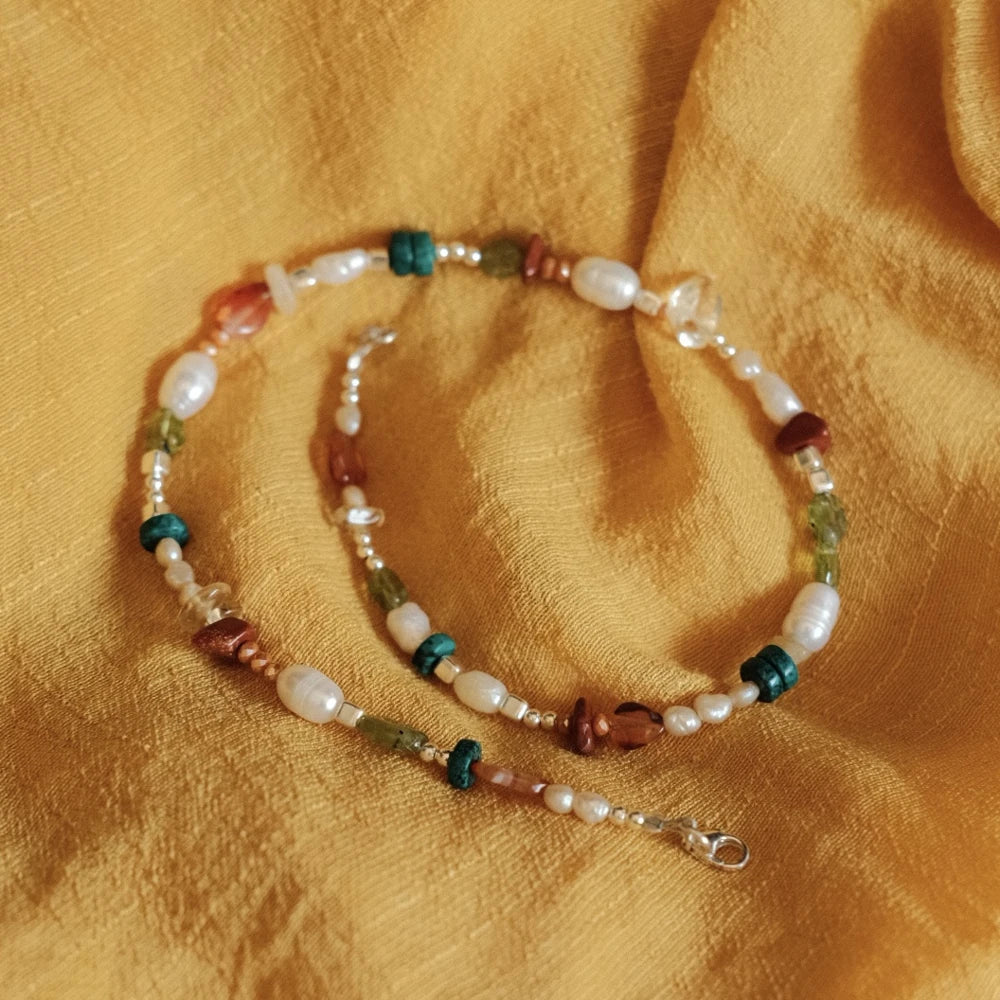 מבט על שרשרת כסף עם אבני חן ופניני מים מתוקים, משלבת גווני תכלת, ירוק ואדום למראה קיצי ואלגנטי.