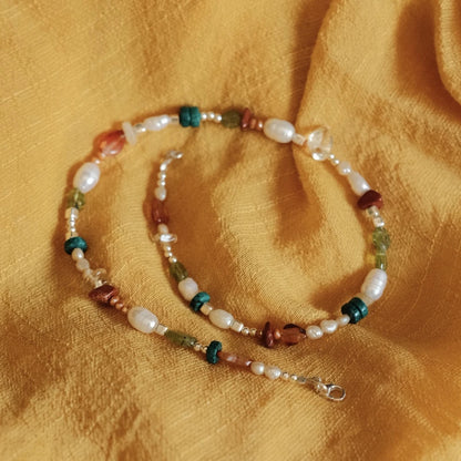 מבט על שרשרת כסף עם אבני חן ופניני מים מתוקים, משלבת גווני תכלת, ירוק ואדום למראה קיצי ואלגנטי.