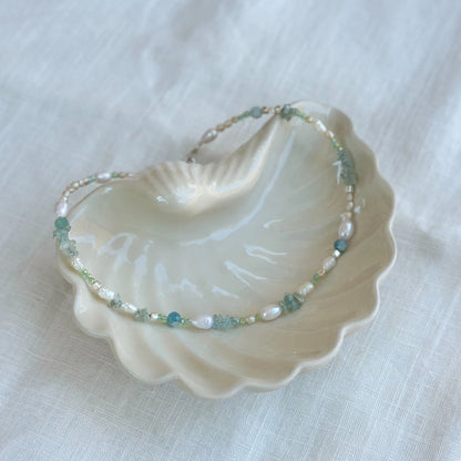 מבט מהצד על שרשרת פנינים ואבני חן בגווני תכלת ולבן, תכשיט בעבודת יד המתאים לאירועים ולמראה יומיומי.