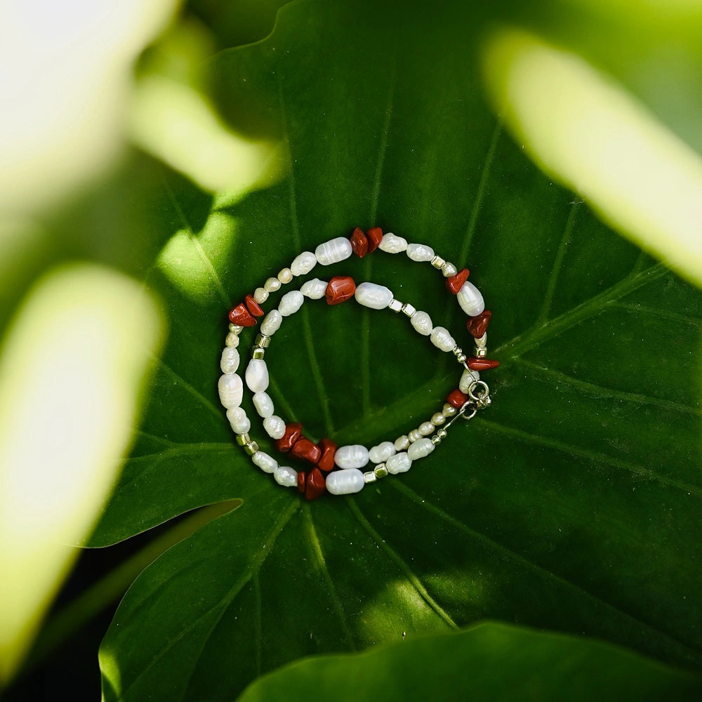 מבט מהצד על שרשרת פנינים ואבני ג'ספר אדומות, עבודת צורפות מוקפדת בהשראת הטבע.