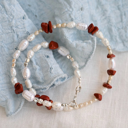 שרשרת כסף עם פנינים לבנות ואבני ג'ספר אדומות על רקע בד תכלת, שילוב צבעים קלאסי ונועז לקולקציית הקיץ של שירו.