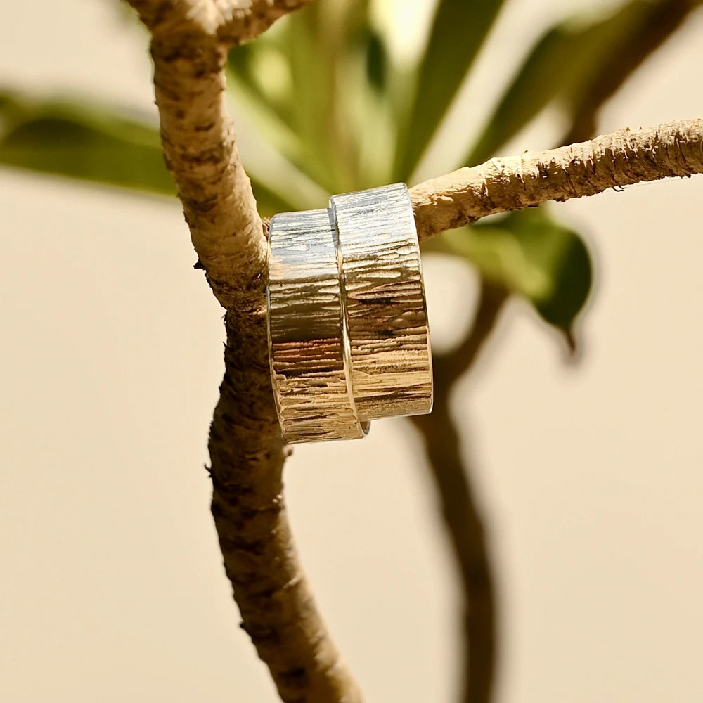 עגילי כסף בעיצוב אורגני תלויים על ענף טבעי, משקפים את השראת הטבע של קולקציית הקיץ.