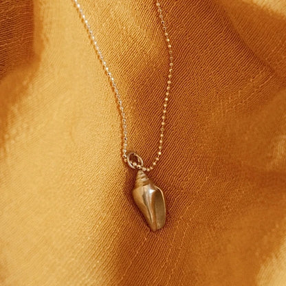 מבט מקרוב על תליון קונכייה מכסף 925 על רקע בד צהוב, המדגיש את הפרטים הקטנים והגימור המוקפד.