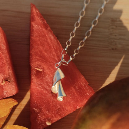 שרשרת כסף 925 עם תליון ספירלת הים בעיצוב אורגני בעבודת יד, מונחת לצד פלח אבטיח רענן מקולקציית הקיץ של Shiroo.