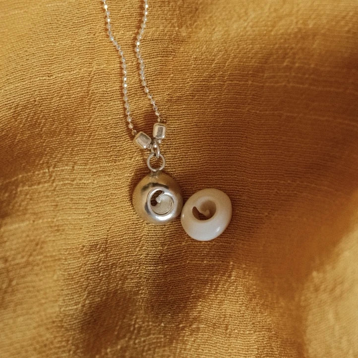 מבט על שני תליוני 'עין הים' מכסף סטרלינג, עבודת צורפות מוקפדת המדגישה את הפרטים הקטנים והעיצוב החד-פעמי.