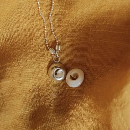 מבט על שני תליוני 'עין הים' מכסף סטרלינג, עבודת צורפות מוקפדת המדגישה את הפרטים הקטנים והעיצוב החד-פעמי.