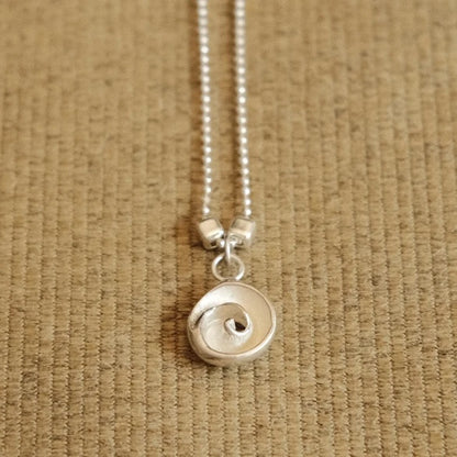 תקריב של שרשרת כסף עדינה עם תליון עין הים, תכשיט אלגנטי המתאים למראה יומיומי או כפריט נלווה לערב.