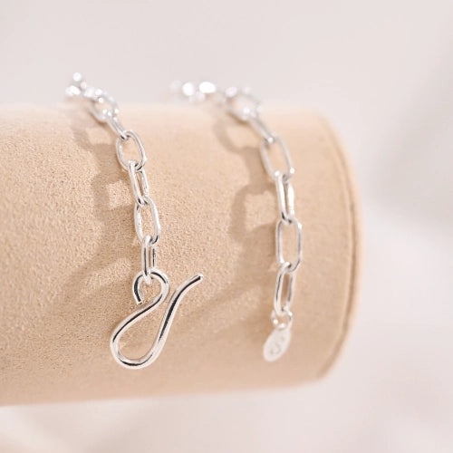 צמיד לולאות כסף סטרלינג קטנות מוצג על מעמד קטיפה, מדגיש את המראה הקלאסי והאלגנטי של התכשיט.