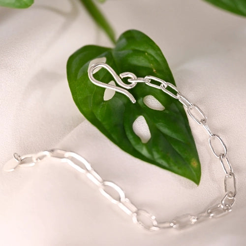 צמיד כסף 925 לולאות מרובעות מיני מונח על עלה ירוק, עיצוב גיאומטרי עדין בעבודת יד של Shiroo.