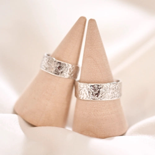 שתי טבעות כסף 925 בעיצוב ריקוע אבן ייחודי על מעמדי עץ, עבודת יד של Shiroo המדמה טקסטורה טבעית וגולמית.
