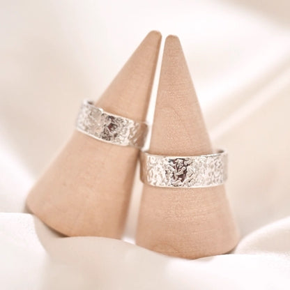 שתי טבעות כסף 925 בעיצוב ריקוע אבן ייחודי על מעמדי עץ, עבודת יד של Shiroo המדמה טקסטורה טבעית וגולמית.