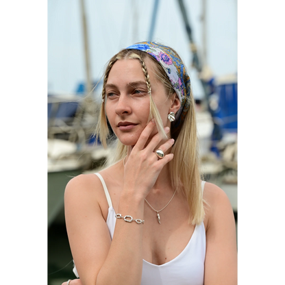 עגילי כסף יוליה של SHIROO, דוגמנית בלונדינית על רקע נמל. בסטיילינג עם שרשרת כסף עם תליון חרב, טבעת כסף גדולה וצמיד כסף חוליות. עגילי כסף סטרלינג 925 תוצרת ישראל.