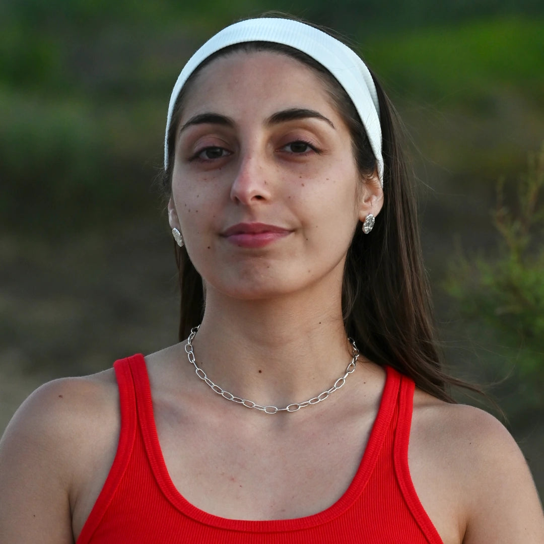 דוגמנית עונדת שרשרת כסף 925 חוליות אובל SHIROO בשילוב עגילי כסף אורגניים – פרונטל, רקע ירוק טבעי, חולצה אדומה, שעת זהב ישראלית. שרשרת כסף חוליות לאישה, משלוח לכל הארץ