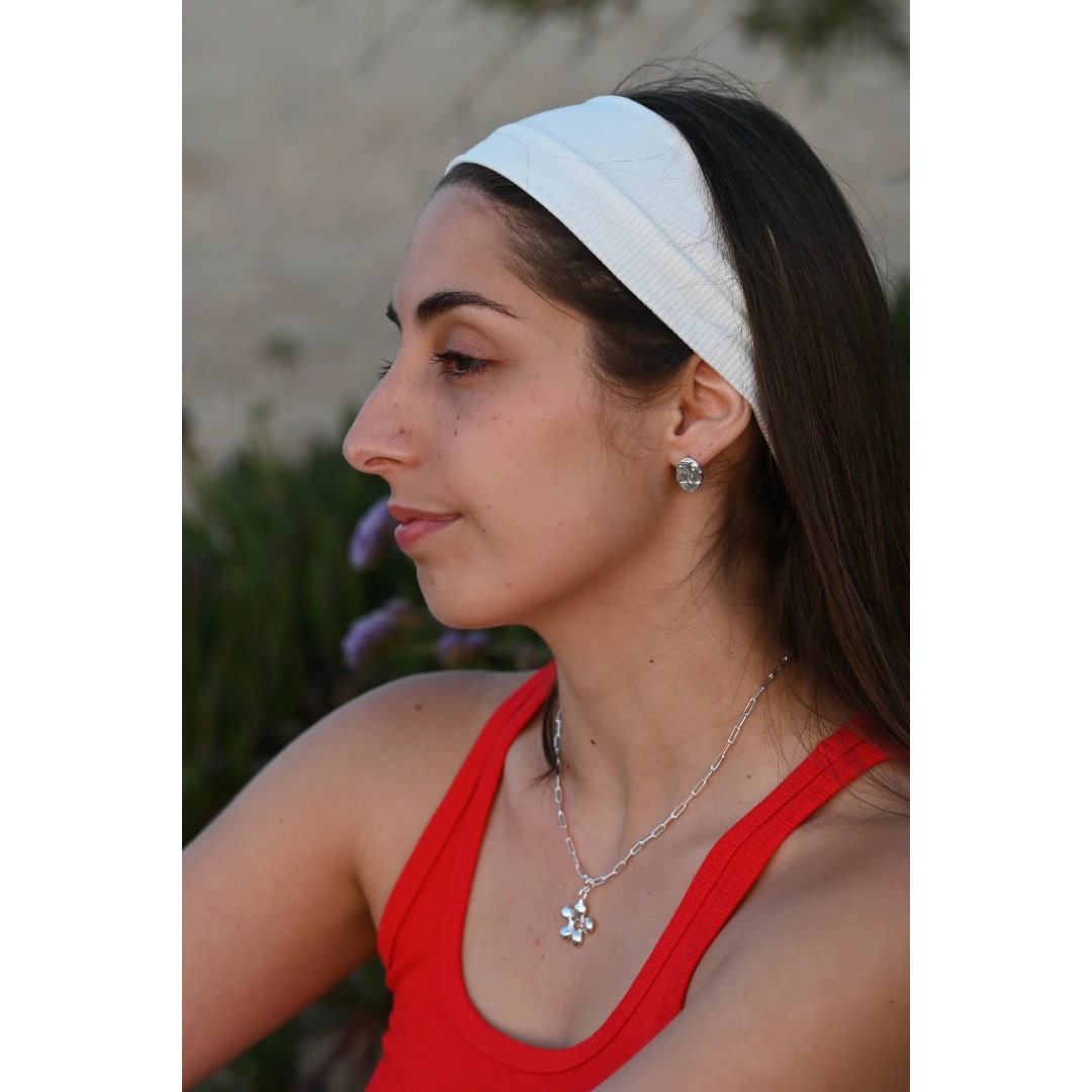 עגילי כסף פיקולה של SHIROO, פרופיל צד של הדוגמנית על רקע פרחים סגולים. בשילוב שרשרת כסף חוליות עם תליון פרח. עגילי כסף 925 עבודת יד תוצרת ישראל.
