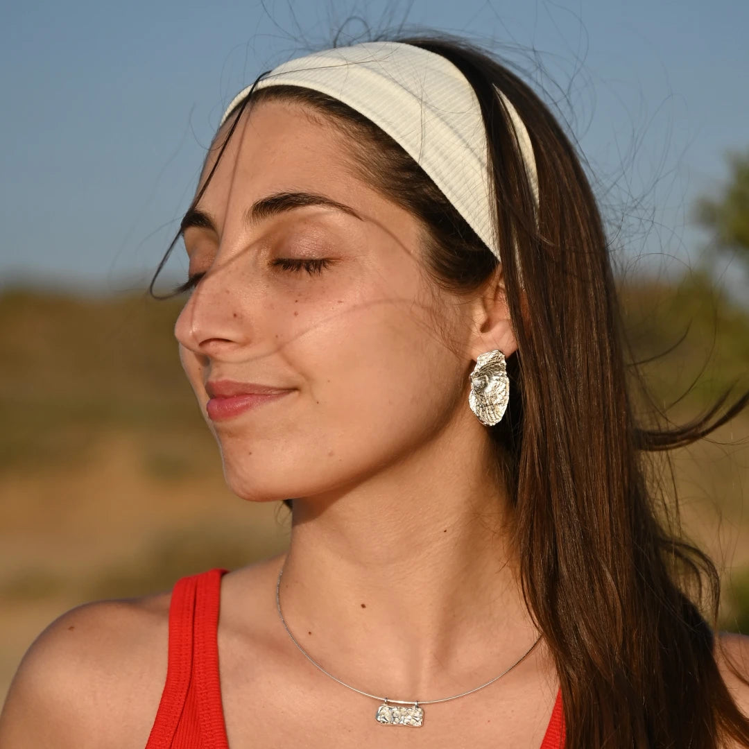 פורטרט דוגמנית עם שרשרת כסף גלים לרוחב SHIROO על צ'וקר קשיח ועגיל כסף אורגני גדול – שמים כחולים, נוף ישראלי. תכשיטי כסף בוטיק לאישה, עיצוב ישראלי מקורי