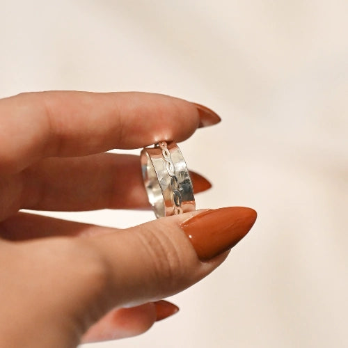 טבעת מסתובבת מכסף בעיצוב רחב ומרשים על היד, תכשיט אמירה המשלב אסתטיקה גבוהה עם פונקציונליות מרגיעה.